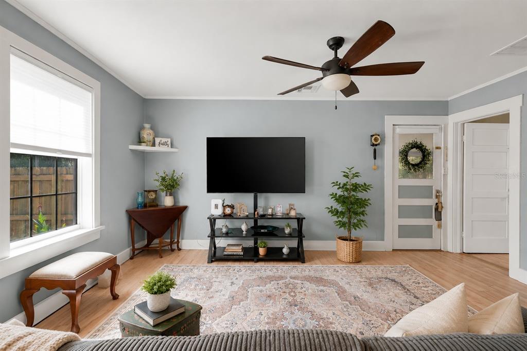 A living room features light blue walls, a ceiling fan, a television, and a patterned rug — 321 CASSADY STREET, UMATILLA, FL