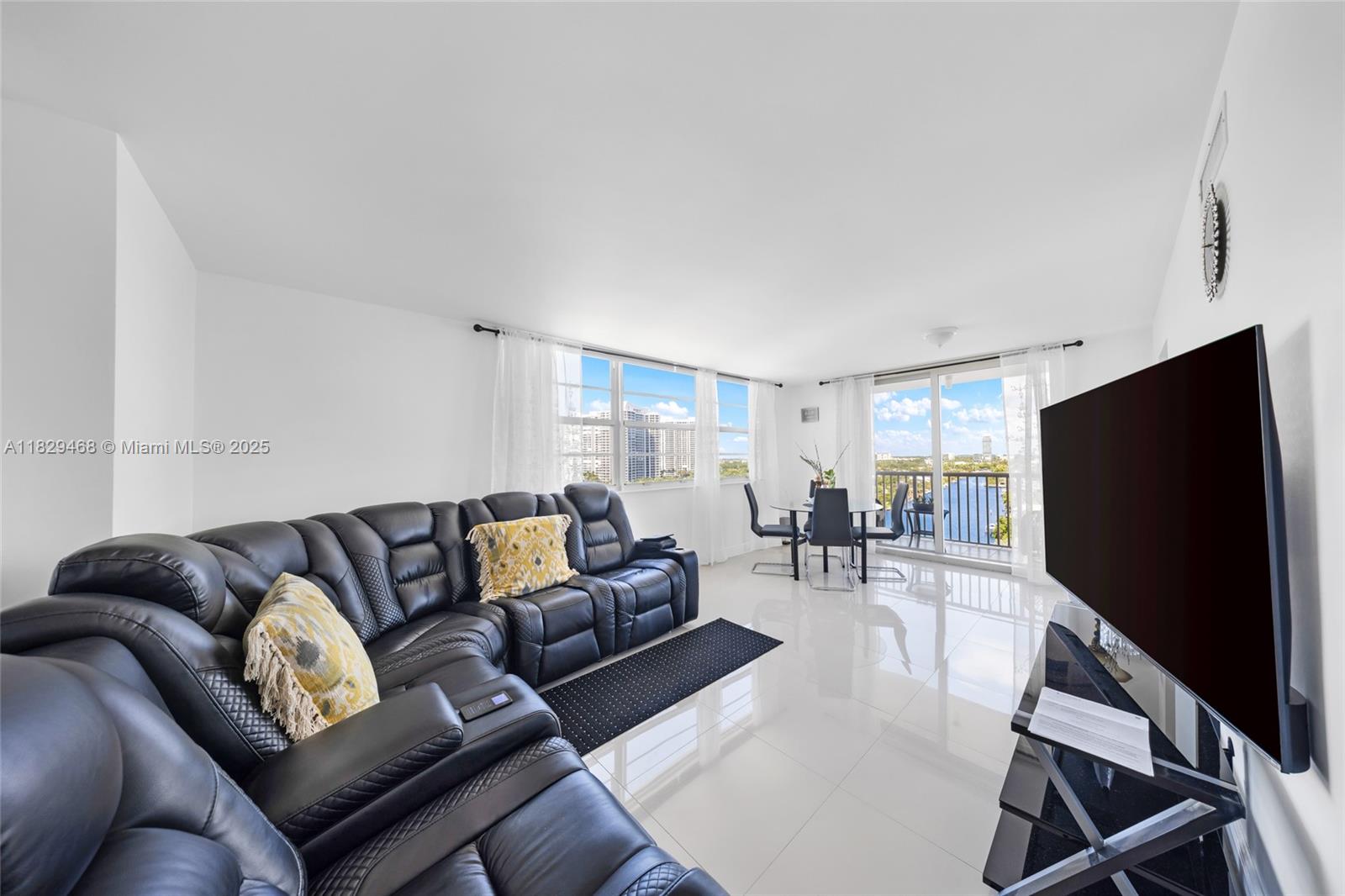 A living room features a black sectional sofa, white tile floors, and a balcony view — 3161 S Ocean Dr # 1510, Hallandale Beach FL 33009, HALLANDALE BEACH, FL