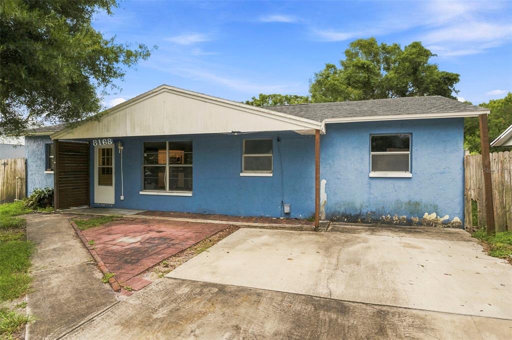 A blue, single-story house with a concrete driveway, a small patio, and a covered entryway — 8168 82ND AVENUE, SEMINOLE, FL