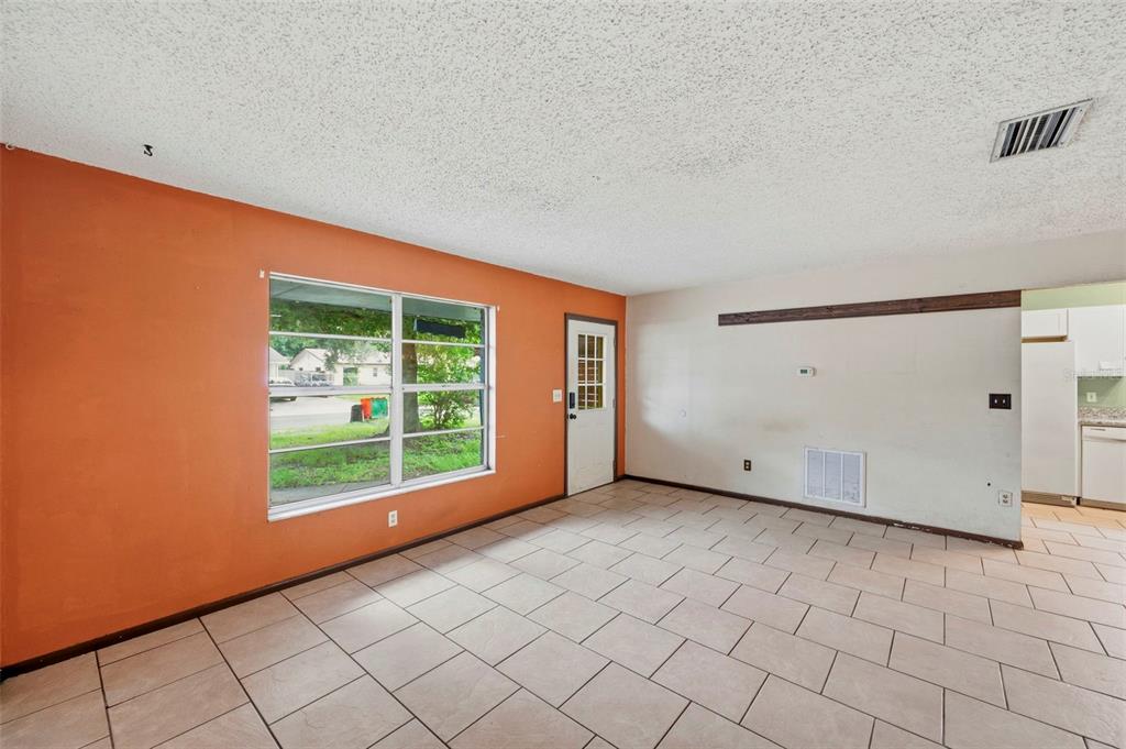 A room with orange and white walls, tile flooring, a large window, and a door — 8168 82ND AVENUE, SEMINOLE, FL