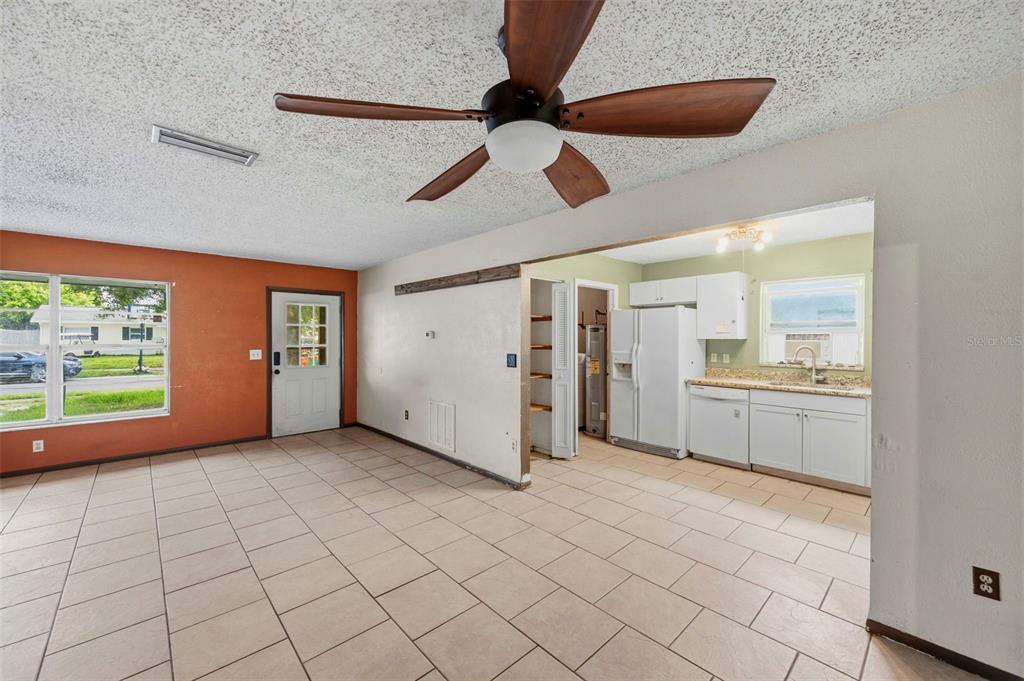 A living room with tile flooring and a ceiling fan opens into a kitchen area — 8168 82ND AVENUE, SEMINOLE, FL