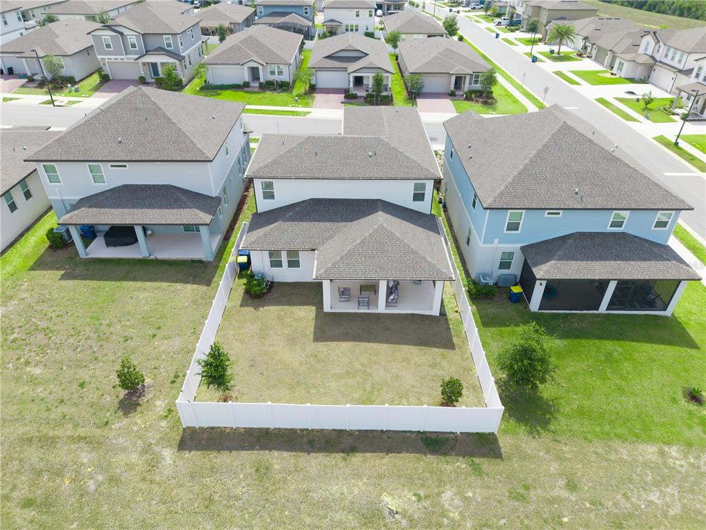 An aerial view shows the backyards and rear exteriors of three suburban residential houses — 2326 RAVEN RIDGE ROAD, MINNEOLA, FL