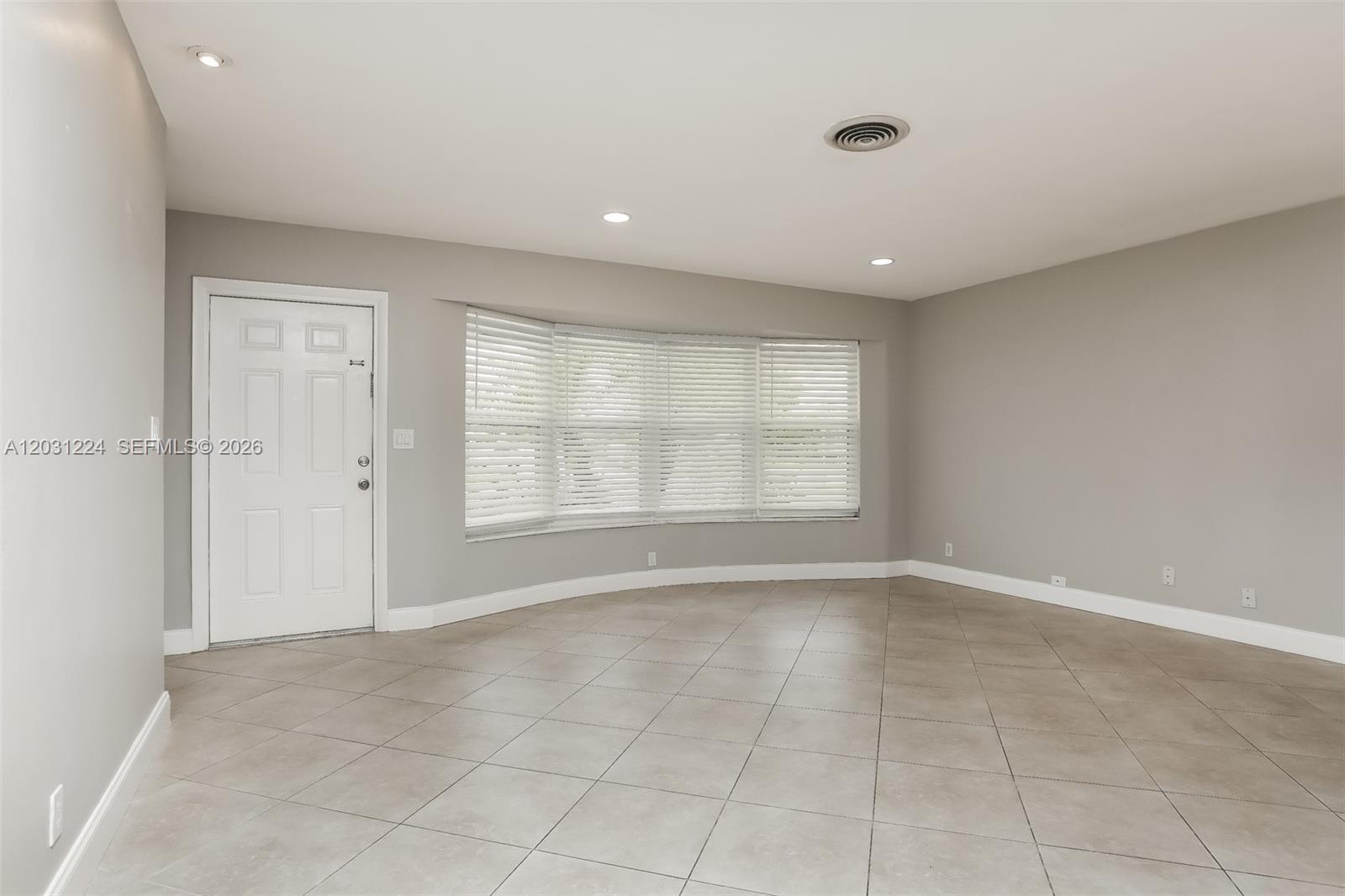 An empty room features light gray walls, large beige floor tiles, and a bay window — 6119 NW 18th Ct, Margate FL 33063, MARGATE, FL