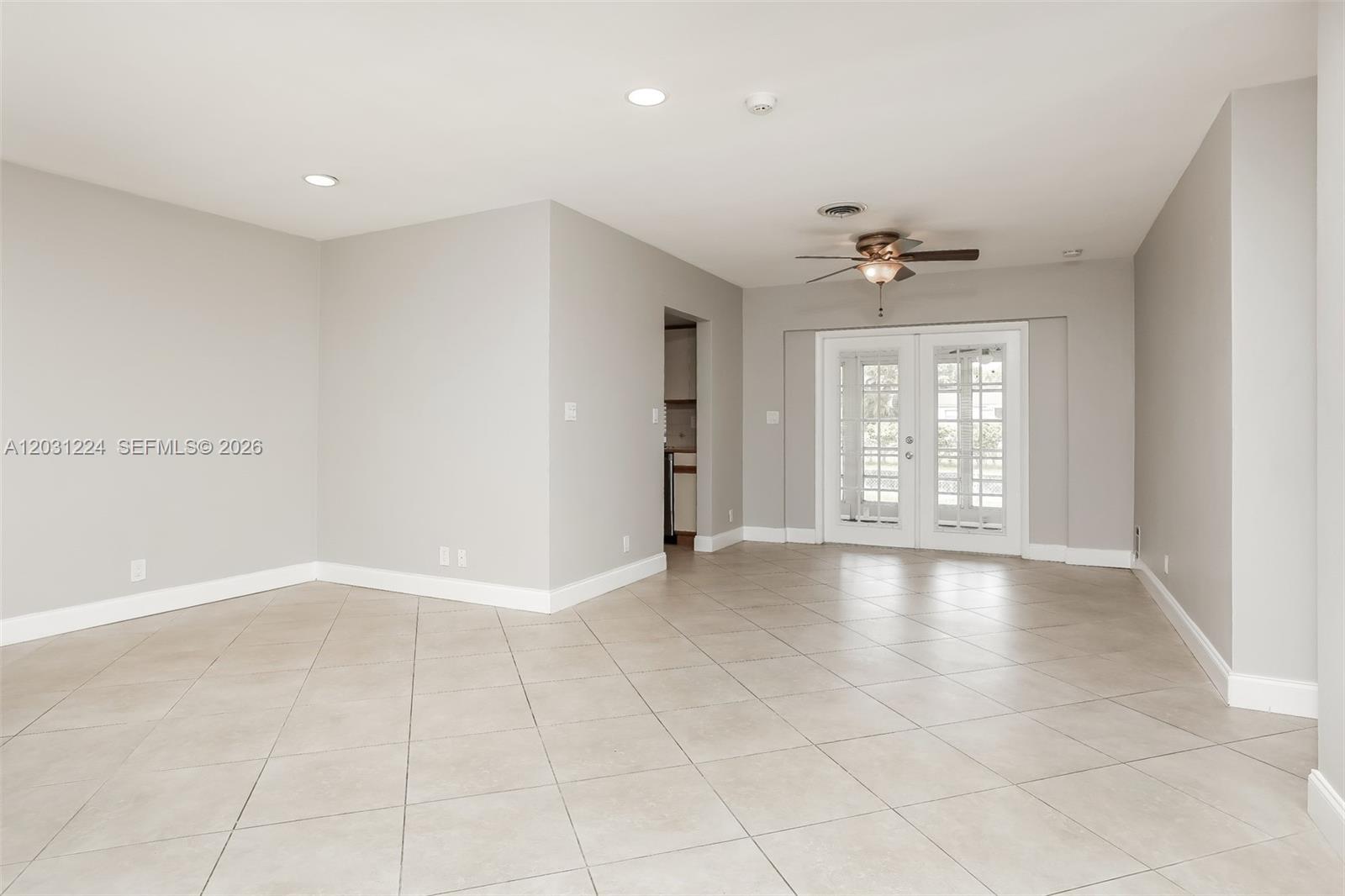 A spacious room with light gray walls, tile flooring, a ceiling fan, and French doors — 6119 NW 18th Ct, Margate FL 33063, MARGATE, FL