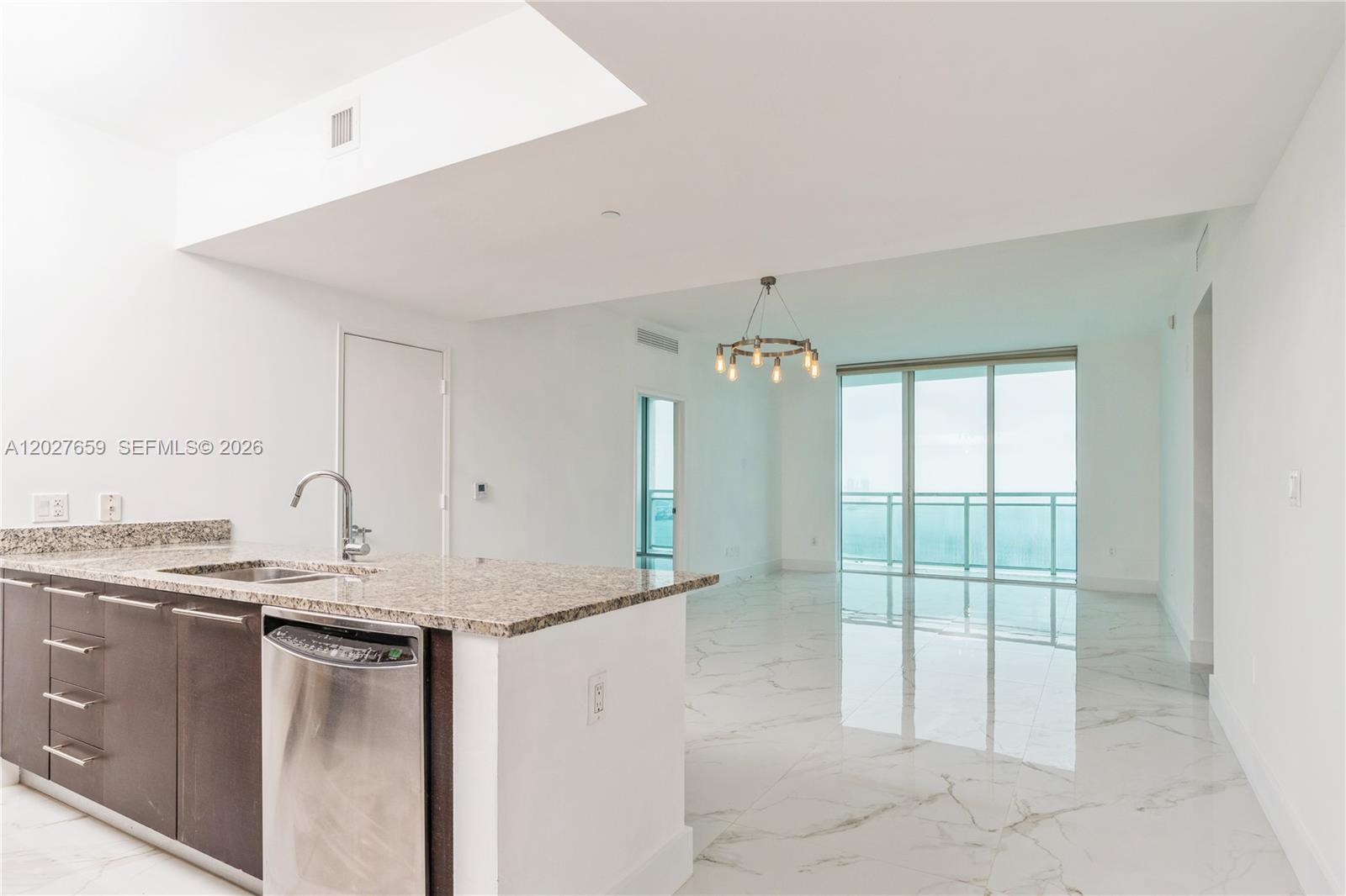 A modern kitchen with granite countertops and stainless steel appliances opens to a living area — 951 Brickell Ave # 3706, Miami FL 33131, MIAMI, FL