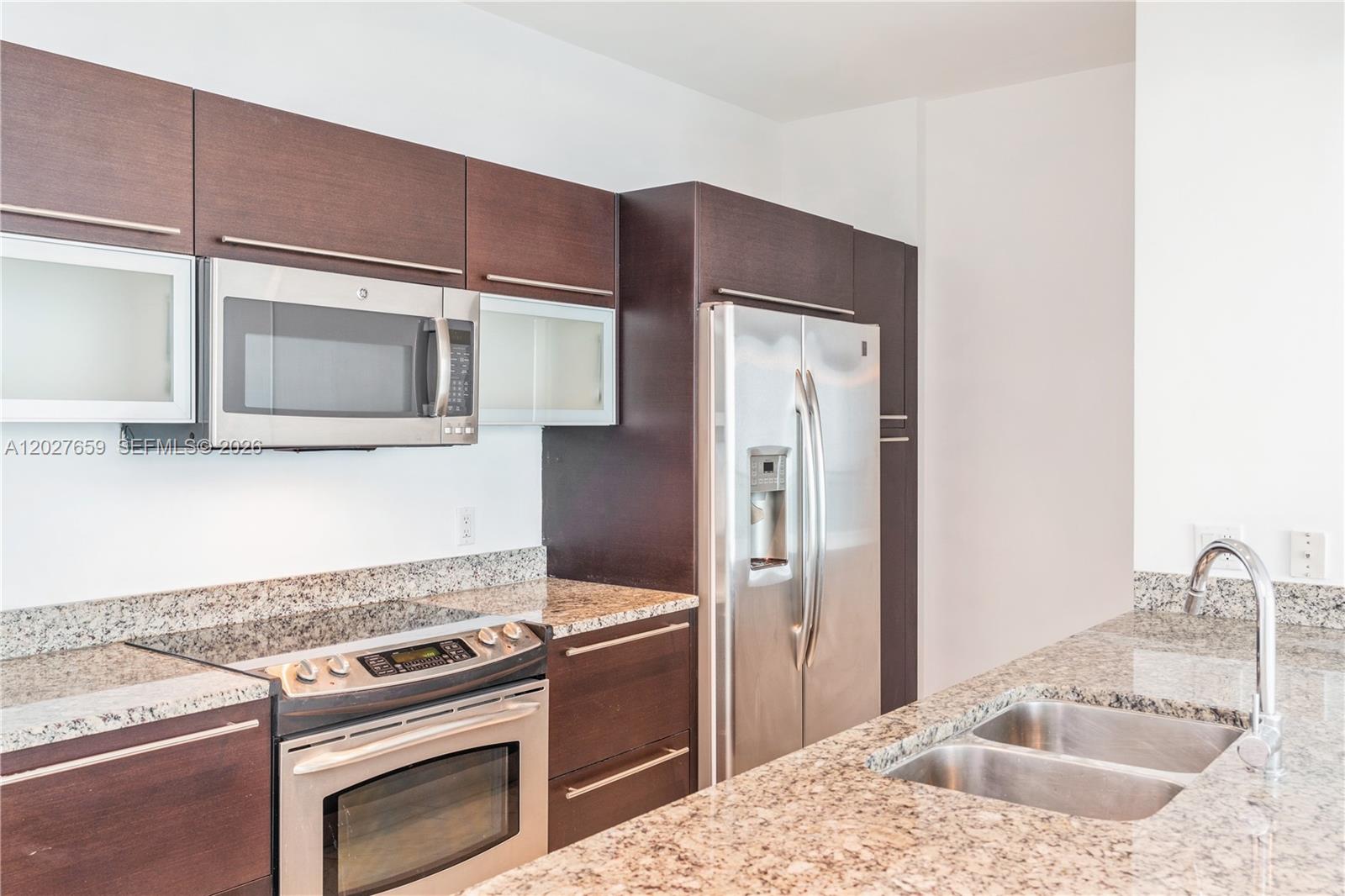 A kitchen features dark wood cabinets, granite countertops, and stainless steel appliances — 951 Brickell Ave # 3706, Miami FL 33131, MIAMI, FL