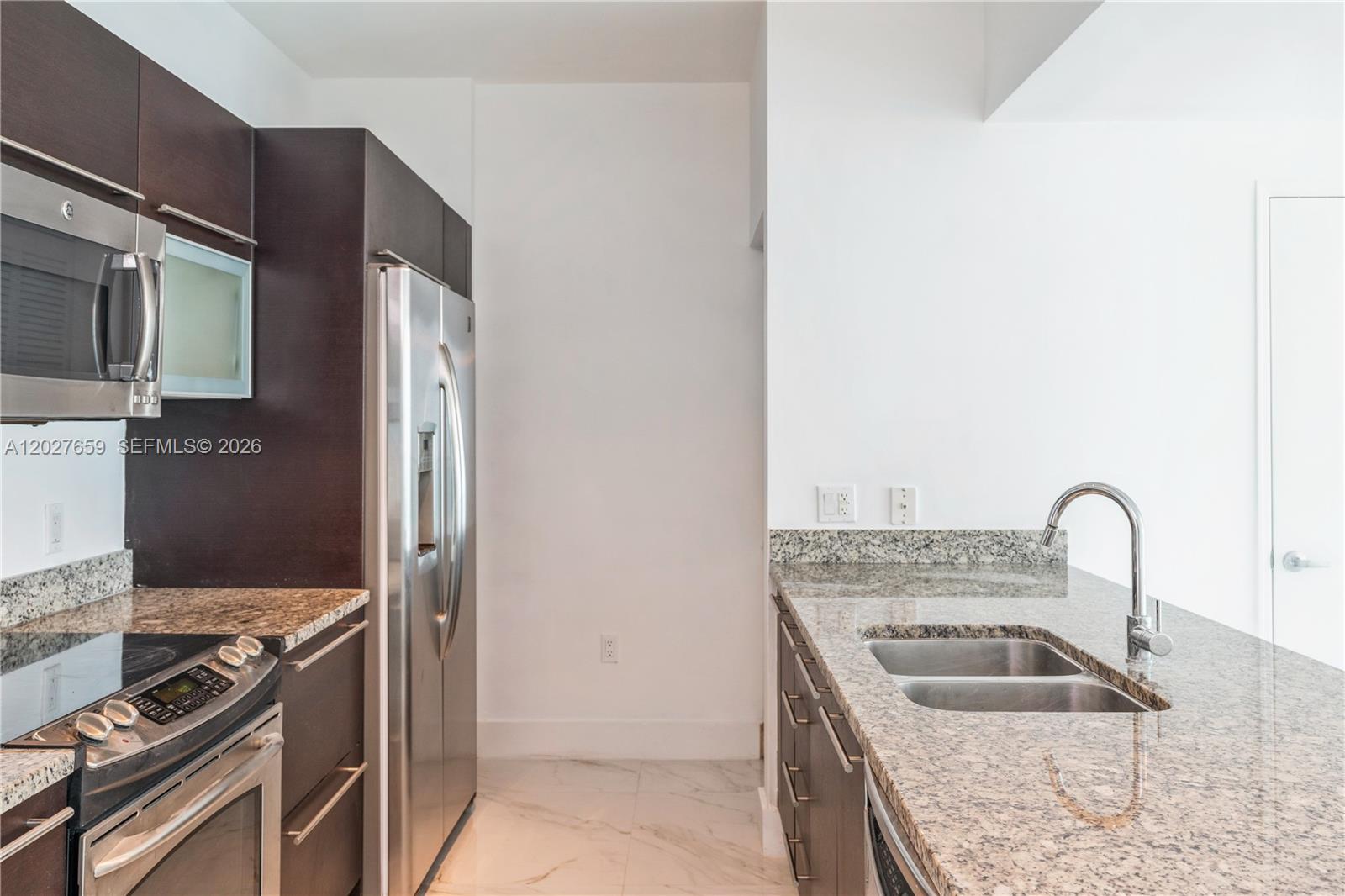 A modern kitchen features dark wood cabinets, granite countertops, and stainless steel appliances — 951 Brickell Ave # 3706, Miami FL 33131, MIAMI, FL