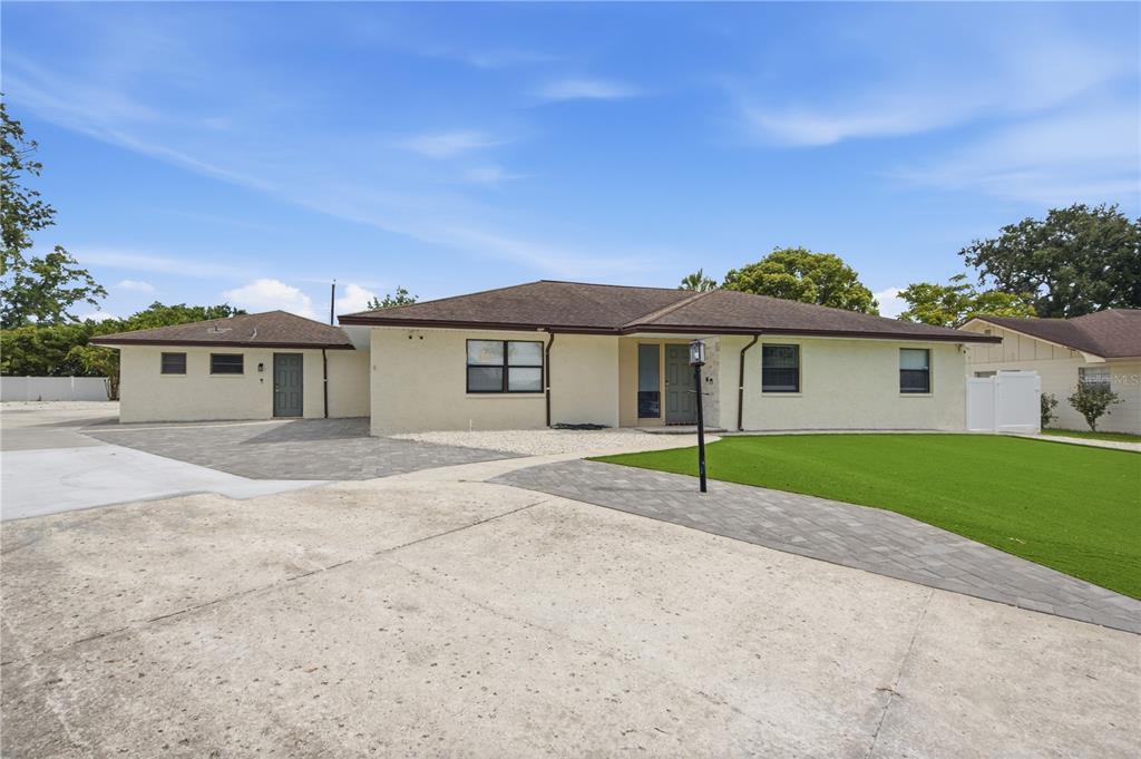A single-story house with a beige stucco exterior, a brown roof, and a paved driveway — 1433 ELLISON LANE, LAKELAND, FL