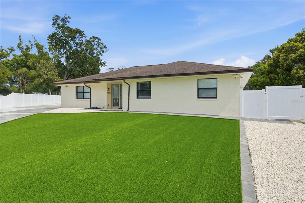 A single-story house with a light-colored stucco exterior, a brown roof, and a green lawn — 1433 ELLISON LANE, LAKELAND, FL