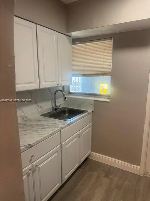 A small kitchen features white cabinets, a stainless steel sink, and marble-patterned countertops — FORT LAUDERDALE, FL