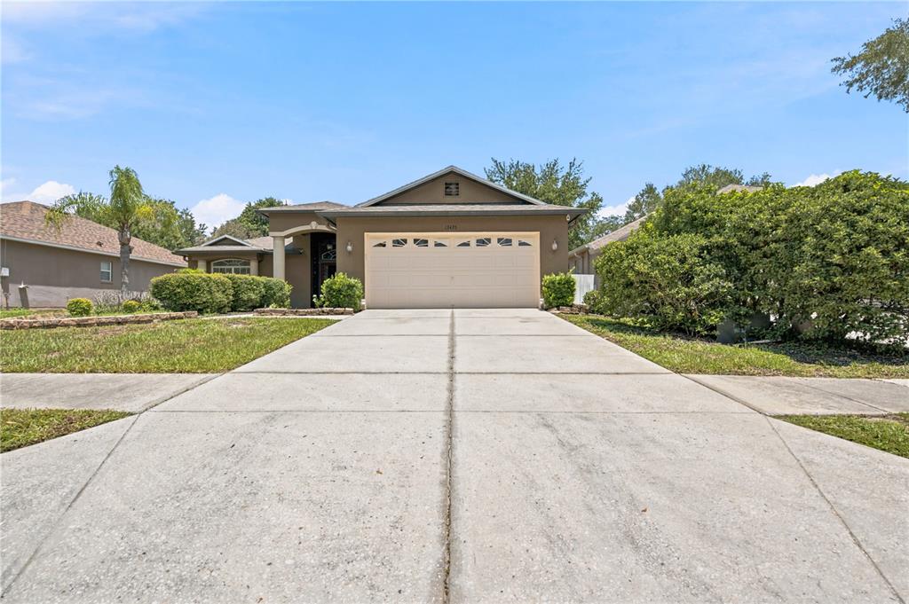 A single-story house with a beige garage door and a concrete driveway — 13475 TEABERRY LANE, SPRING HILL, FL