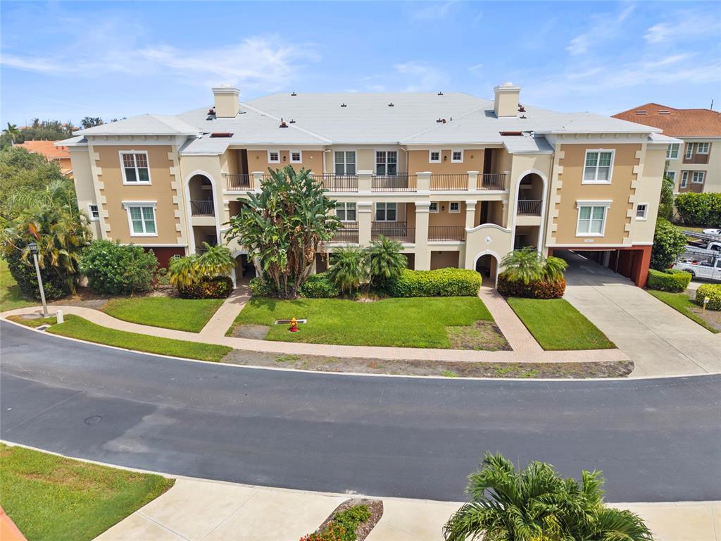A three-story apartment building with a tan facade, balconies, and a paved driveway — 10 FRANKLIN COURT S UNIT 63C, ST PETERSBURG, FL