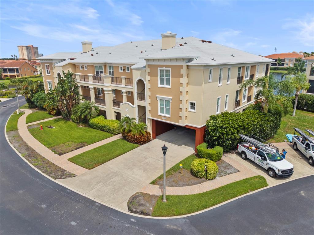 An exterior view of a three-story tan apartment building with a ground-level parking garage — 10 FRANKLIN COURT S UNIT 63C, ST PETERSBURG, FL