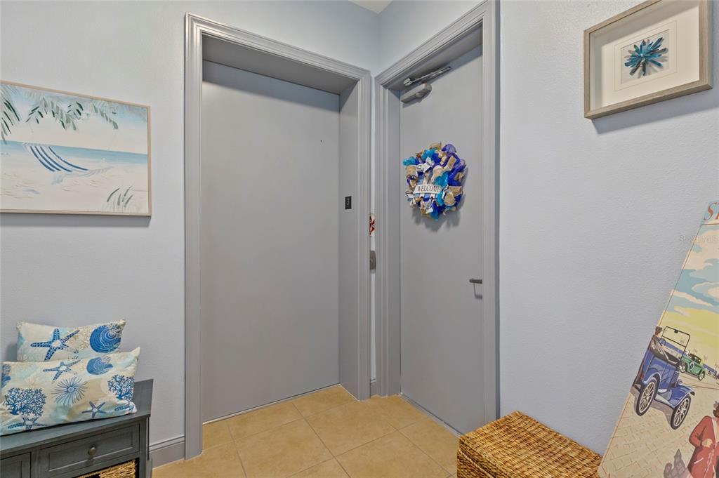 An interior entryway features two gray doors, light blue walls, and coastal-themed decor — 10 FRANKLIN COURT S UNIT 63C, ST PETERSBURG, FL