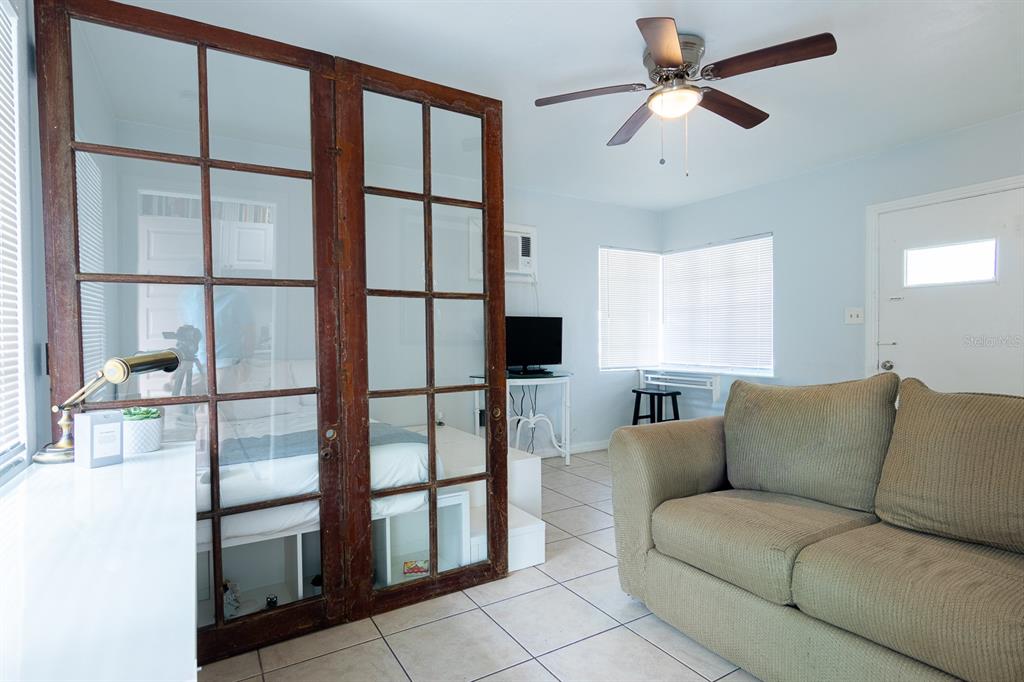 A living area features a sofa, tile floors, a ceiling fan, and a glass-paneled room divider — 610 N EAST AVENUE, SARASOTA, FL