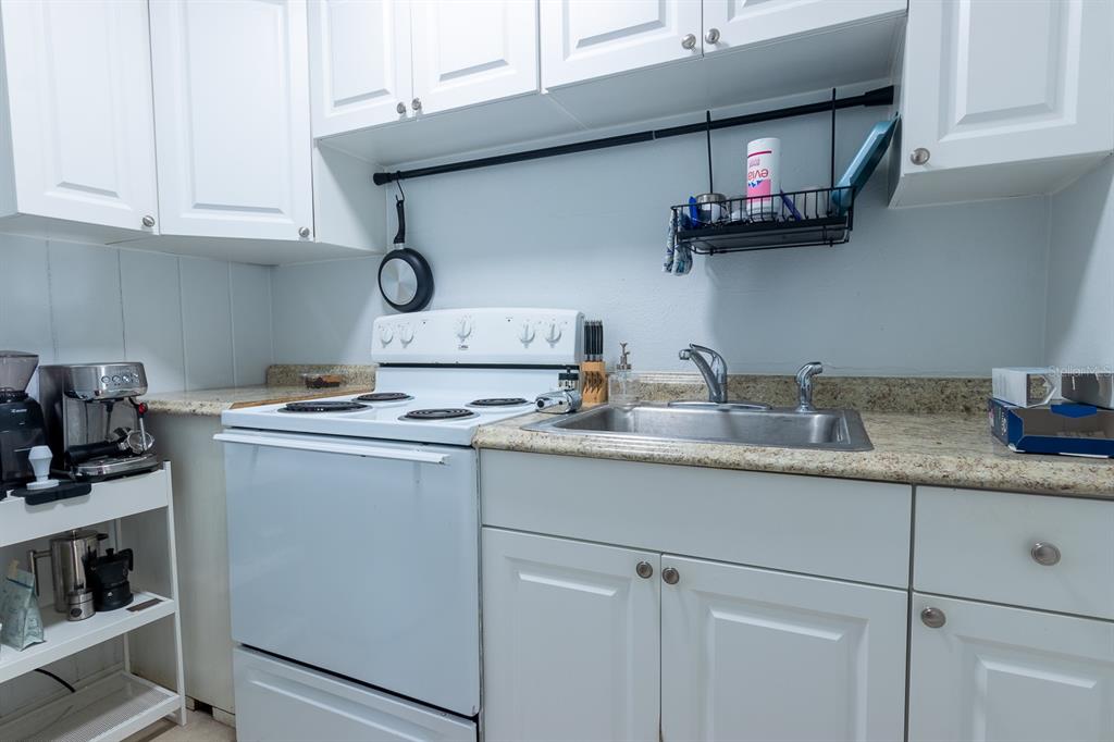 A kitchen features white cabinets, a white electric stove, and a stainless steel sink — 610 N EAST AVENUE, SARASOTA, FL