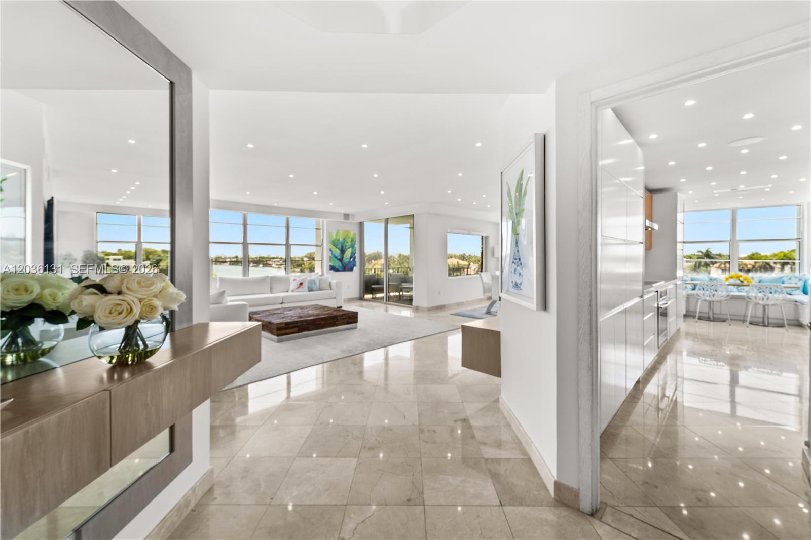 A bright, open-concept living area and kitchen feature white cabinetry, marble floors, and water views — 5640 Collins Ave # 4D, Miami Beach FL 33140, MIAMI BEACH, FL