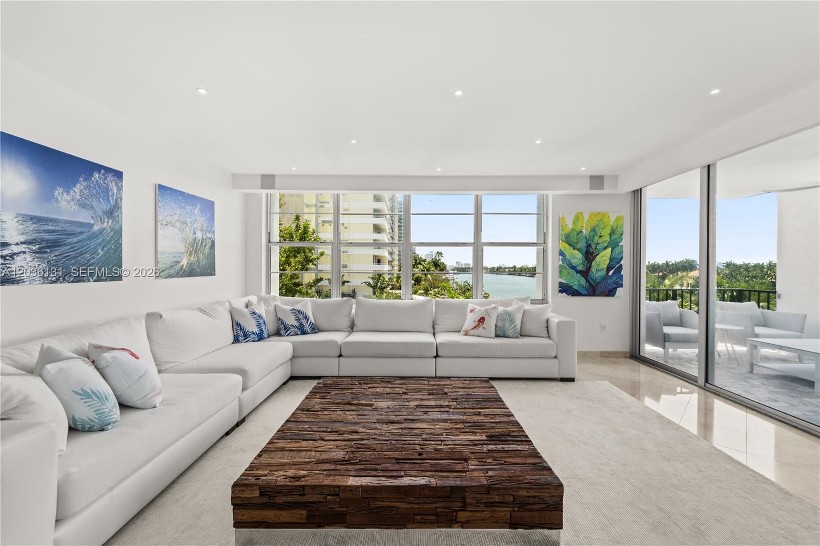 A bright living room features a large white sectional, wooden coffee table, and balcony access — 5640 Collins Ave # 4D, Miami Beach FL 33140, MIAMI BEACH, FL