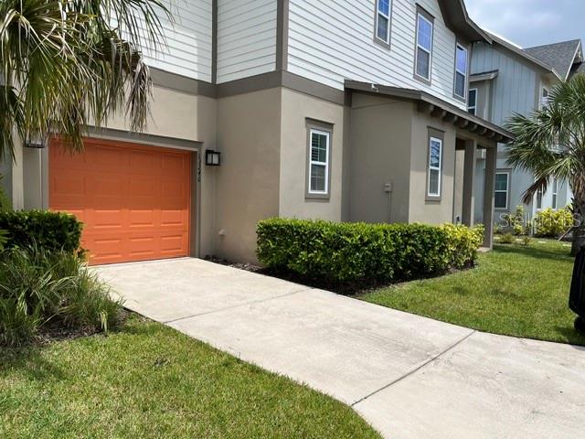 A two-story house features a bright orange garage door, beige siding, and a concrete driveway — 13246 DOISY STREET, ORLANDO, FL