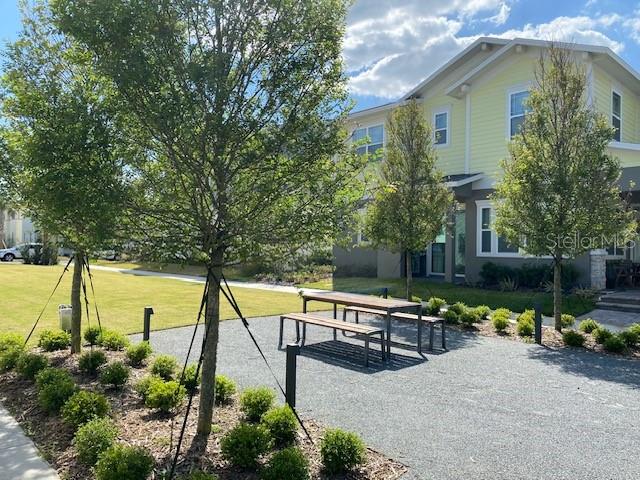 A picnic table sits on a gravel patio in front of a yellow two-story house — 13246 DOISY STREET, ORLANDO, FL