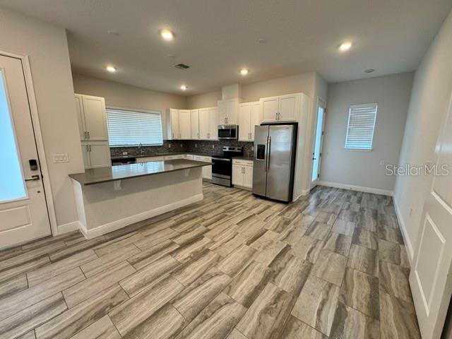 A kitchen features white cabinets, stainless steel appliances, a breakfast bar, and wood-look tile flooring — 13246 DOISY STREET, ORLANDO, FL