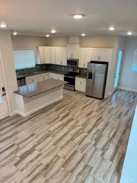 A kitchen features white cabinets, stainless steel appliances, a breakfast bar, and wood-look tile flooring — 13246 DOISY STREET, ORLANDO, FL