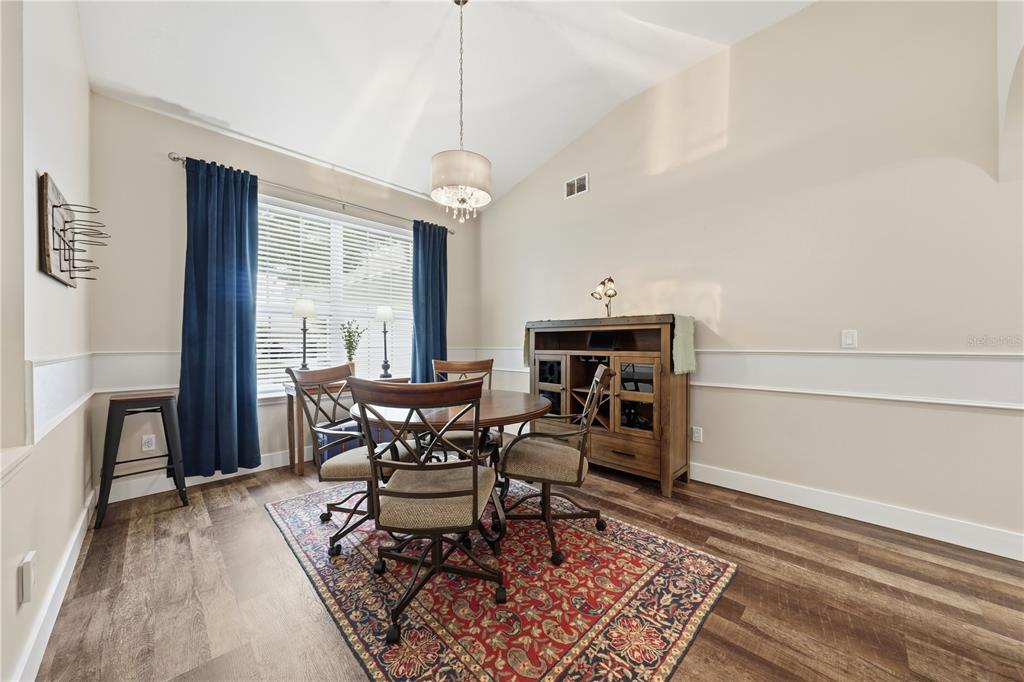 A dining room features a round table, four chairs, a wooden sideboard, and a patterned rug — 2360 PARK FOREST BOULEVARD, MOUNT DORA, FL
