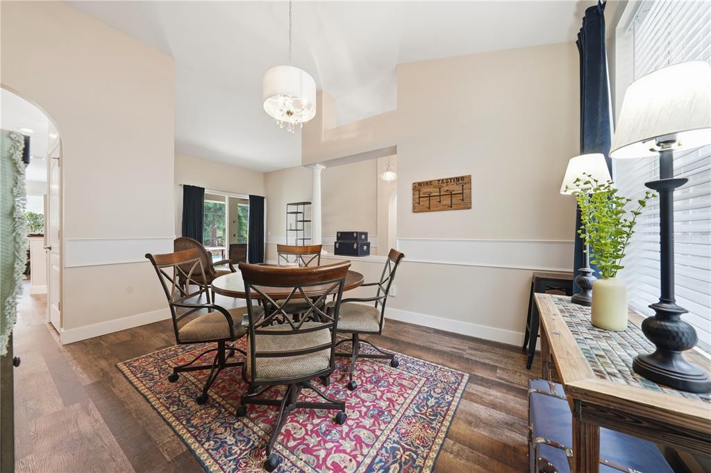 A dining room features a round table, rolling chairs, a patterned rug, and a chandelier — 2360 PARK FOREST BOULEVARD, MOUNT DORA, FL