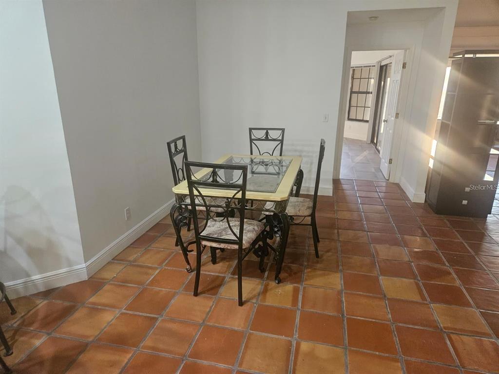 A dining area features a glass-topped table with four metal chairs on terracotta tile flooring — 123 COVENTRY LANE, HAINES CITY, FL