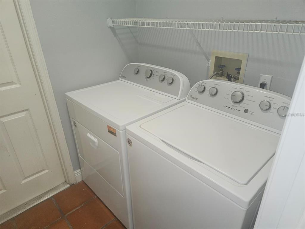 A laundry room features a white washer and dryer set beneath a wire shelf — 123 COVENTRY LANE, HAINES CITY, FL