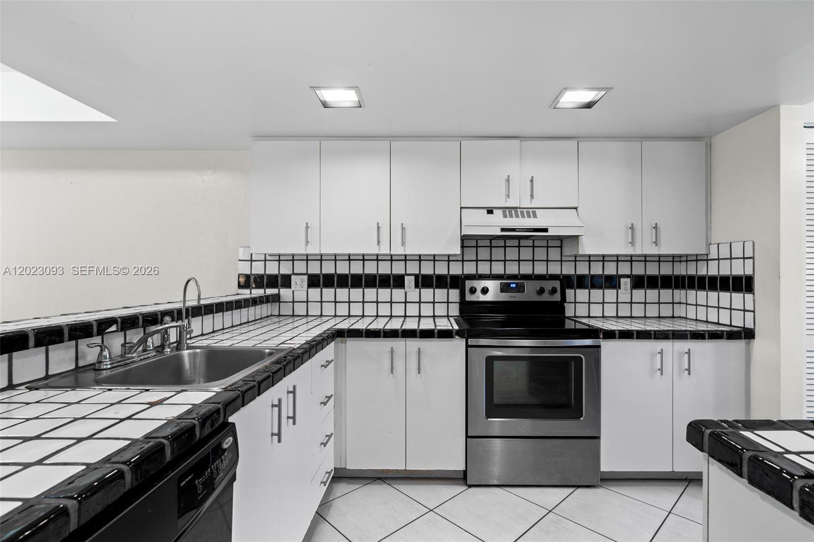 A kitchen features white cabinets, stainless steel appliances, and black-and-white tiled countertops and backsplash — 4241 SW 71st Way # 4241, Davie FL 33314, DAVIE, FL