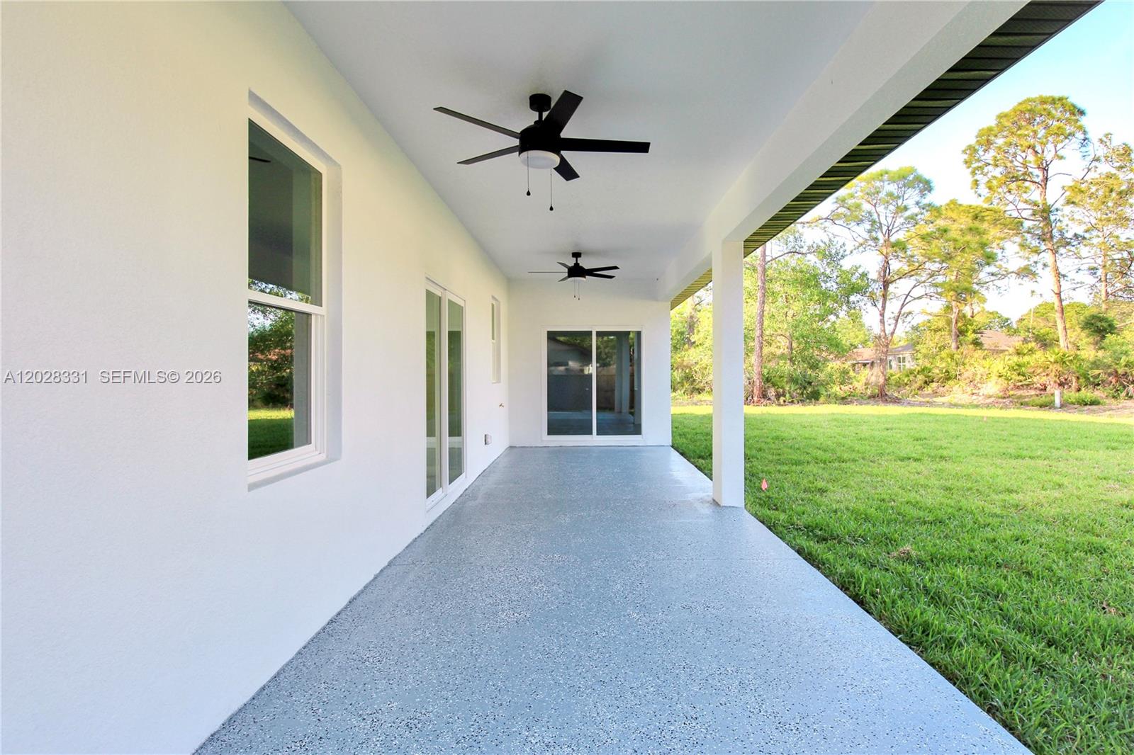 A covered patio features a gray speckled floor, two ceiling fans, and sliding glass doors — 4000 GARIENDA AVE, Sebring FL 33872, SEBRING, FL
