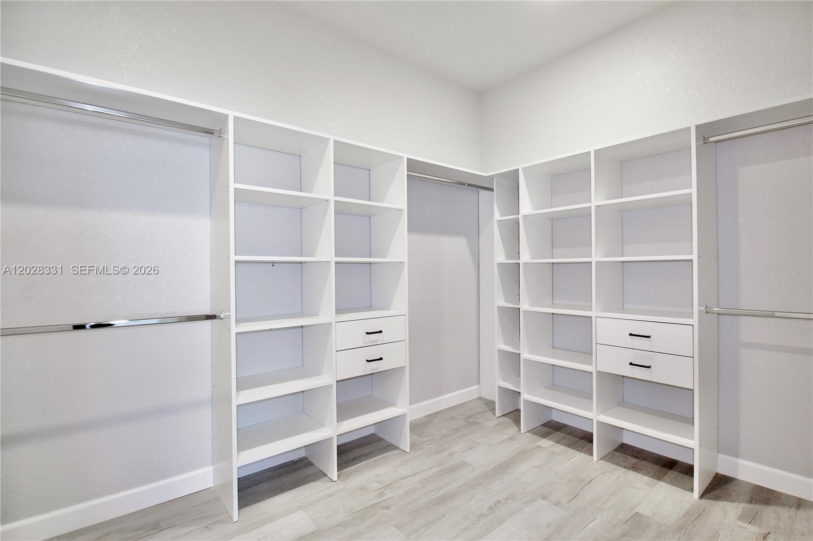 A walk-in closet features white shelving units, built-in drawers, and metal clothing rods — 4000 GARIENDA AVE, Sebring FL 33872, SEBRING, FL