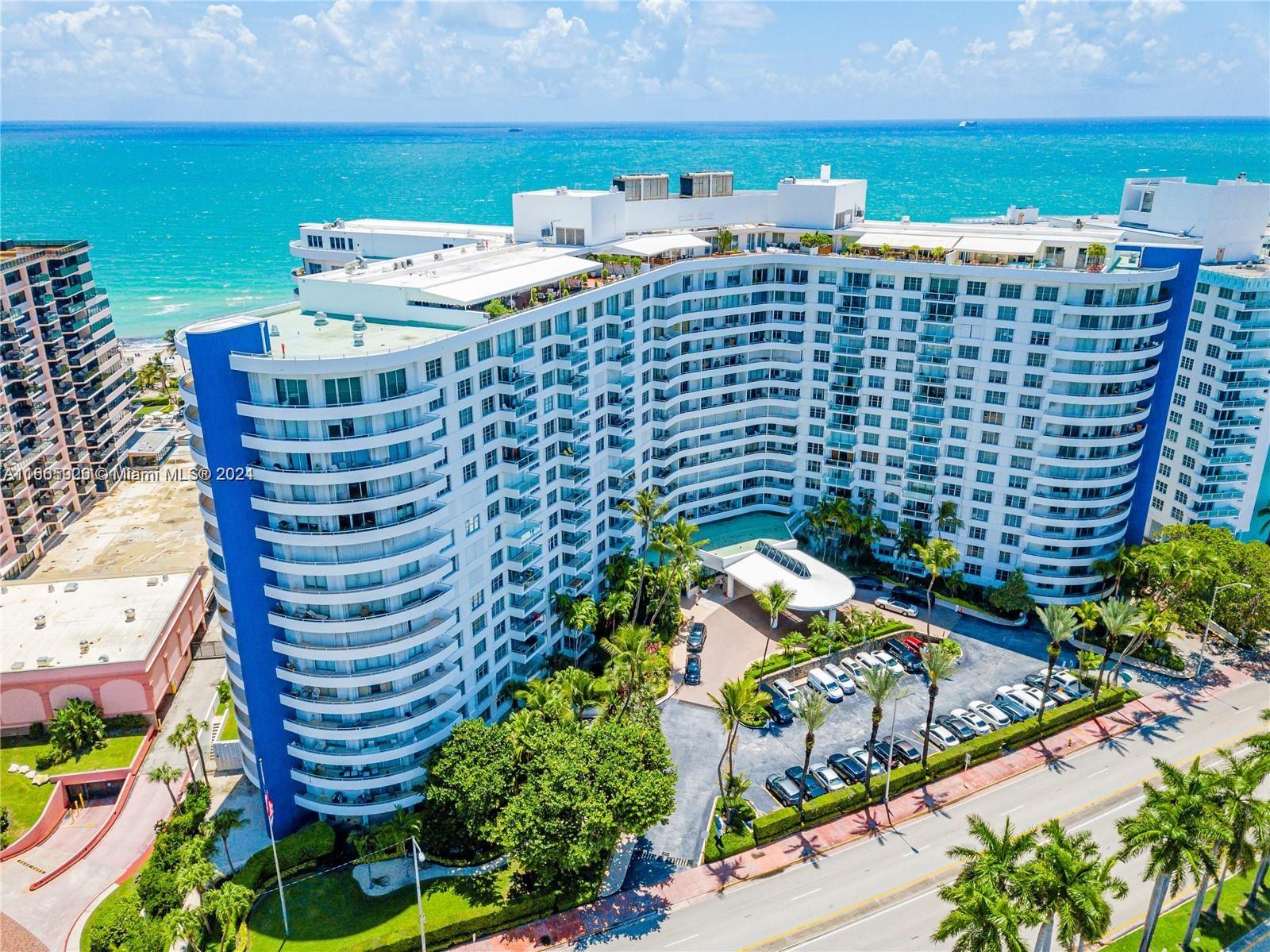 An aerial view shows a large, curved residential building with a pool and parking lot — 5161 Collins Ave # 405, Miami Beach FL 33140, MIAMI BEACH, FL