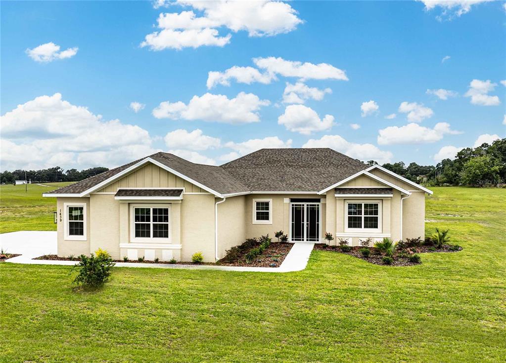 A single-story tan stucco house with a shingled roof sits on a grassy lot — 1439 CR 212, OXFORD, FL