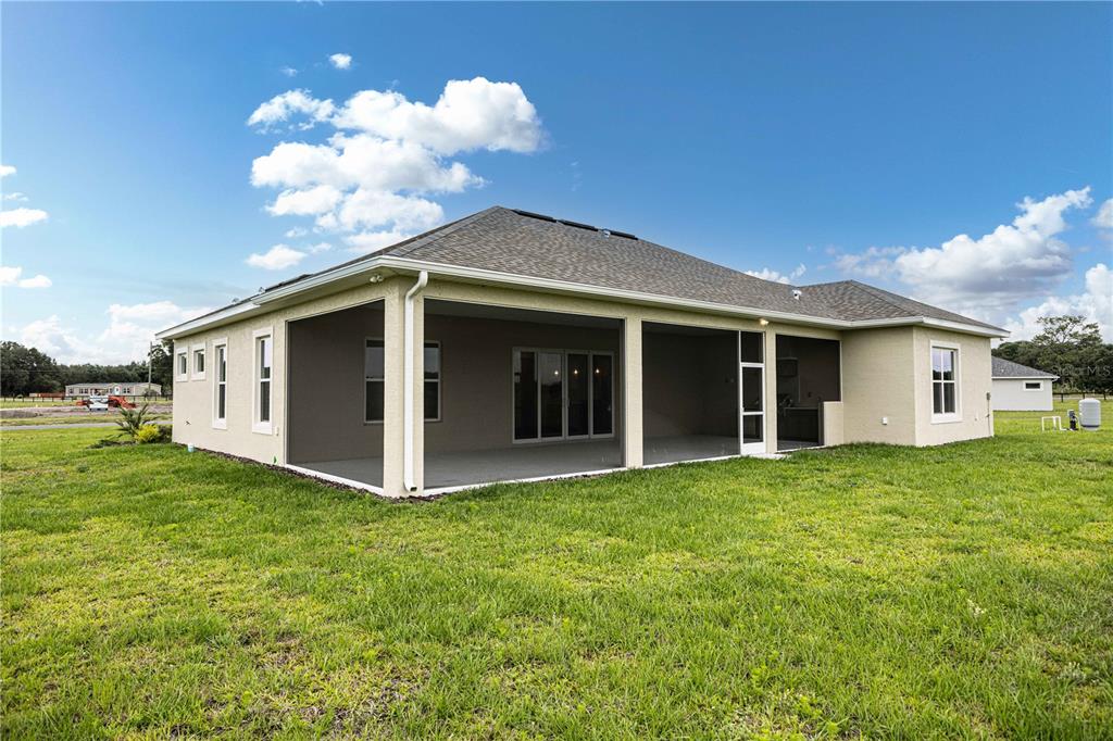 The rear exterior of a single-story house features a large screened-in patio and lawn — 1439 CR 212, OXFORD, FL