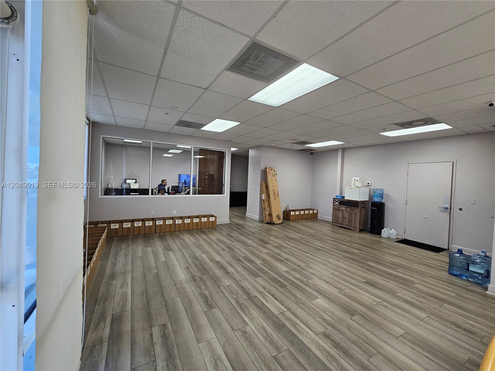 An office space features wood-look flooring, a drop ceiling, and a glass-walled interior room — 9613 NW 33rd St, Doral FL 33172, DORAL, FL