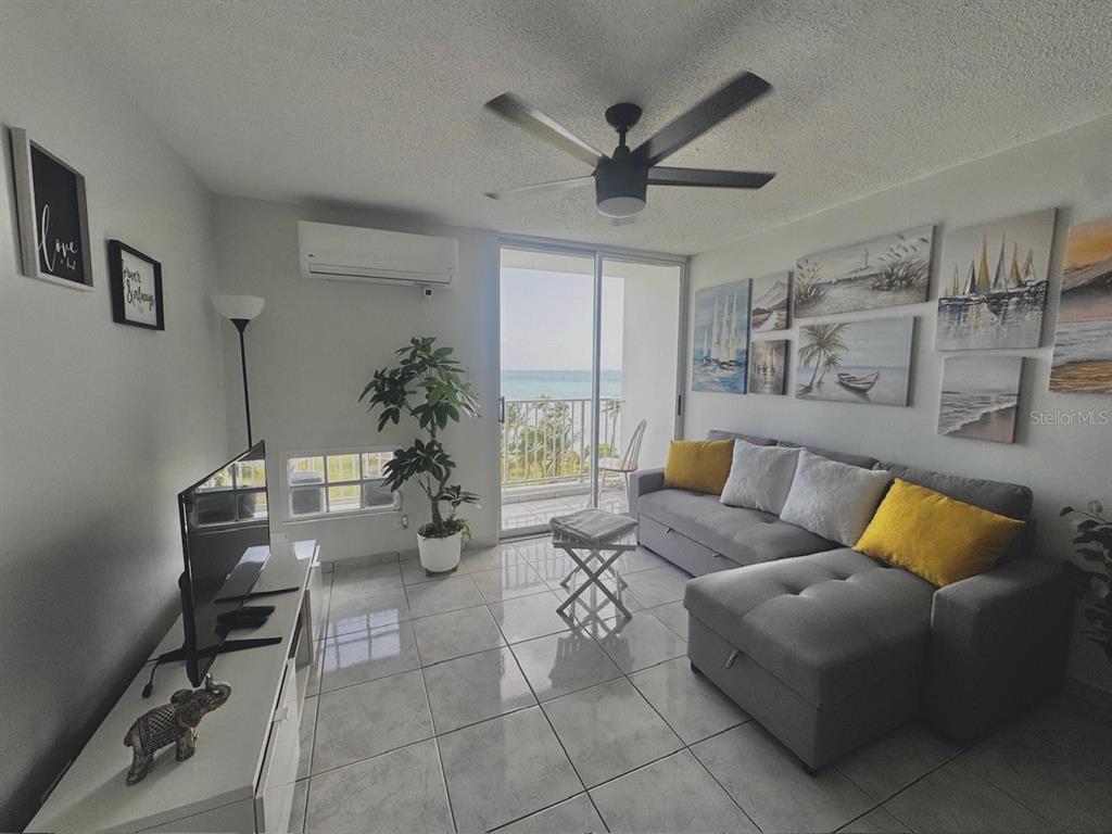 A living room features tile flooring, a gray sectional sofa, and a balcony with ocean views — Islote Cayo Obispo ISLETA MARINA UNIT 6-S, FAJARDO, PR