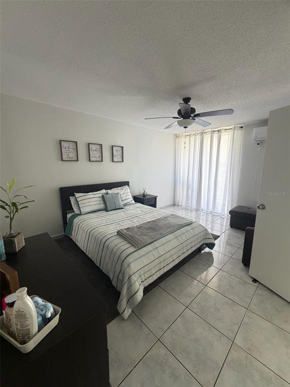 A bedroom with a queen bed, tiled floors, a ceiling fan, and a sliding glass door — Islote Cayo Obispo ISLETA MARINA UNIT 6-S, FAJARDO, PR