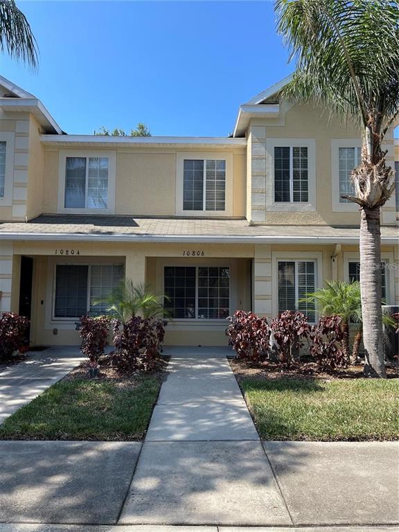 A two-story townhouse exterior features beige siding, white trim, and a palm tree — 10806 BRICKSIDE COURT, RIVERVIEW, FL