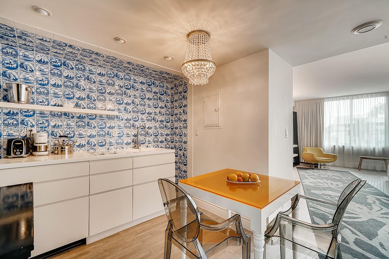 A kitchen features blue and white patterned wall tiles, white cabinetry, and a dining table — 1100 West Ave # 307, Miami Beach FL 33139, MIAMI BEACH, FL