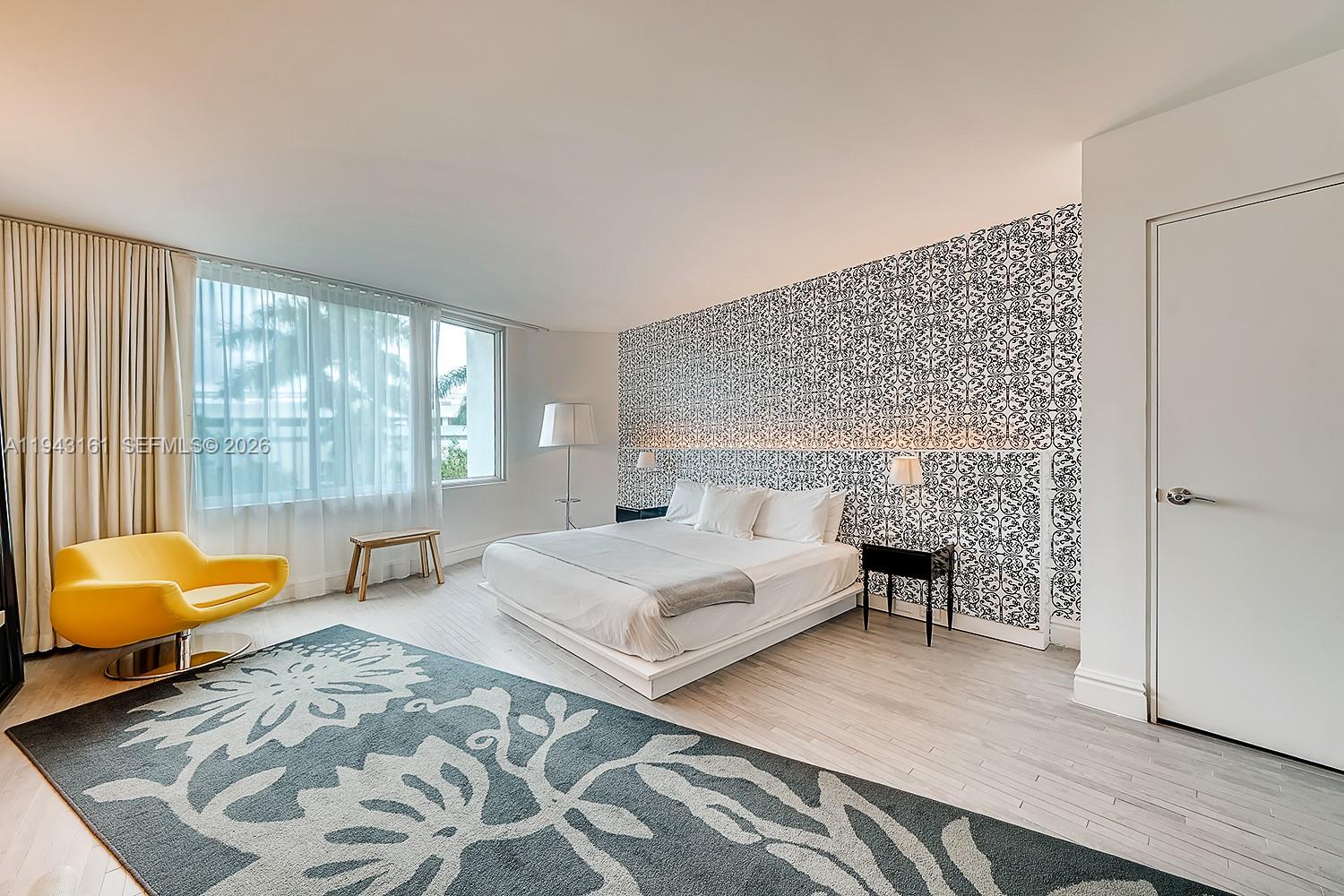 A bedroom features a patterned accent wall, a platform bed, and a yellow swivel chair — 1100 West Ave # 307, Miami Beach FL 33139, MIAMI BEACH, FL