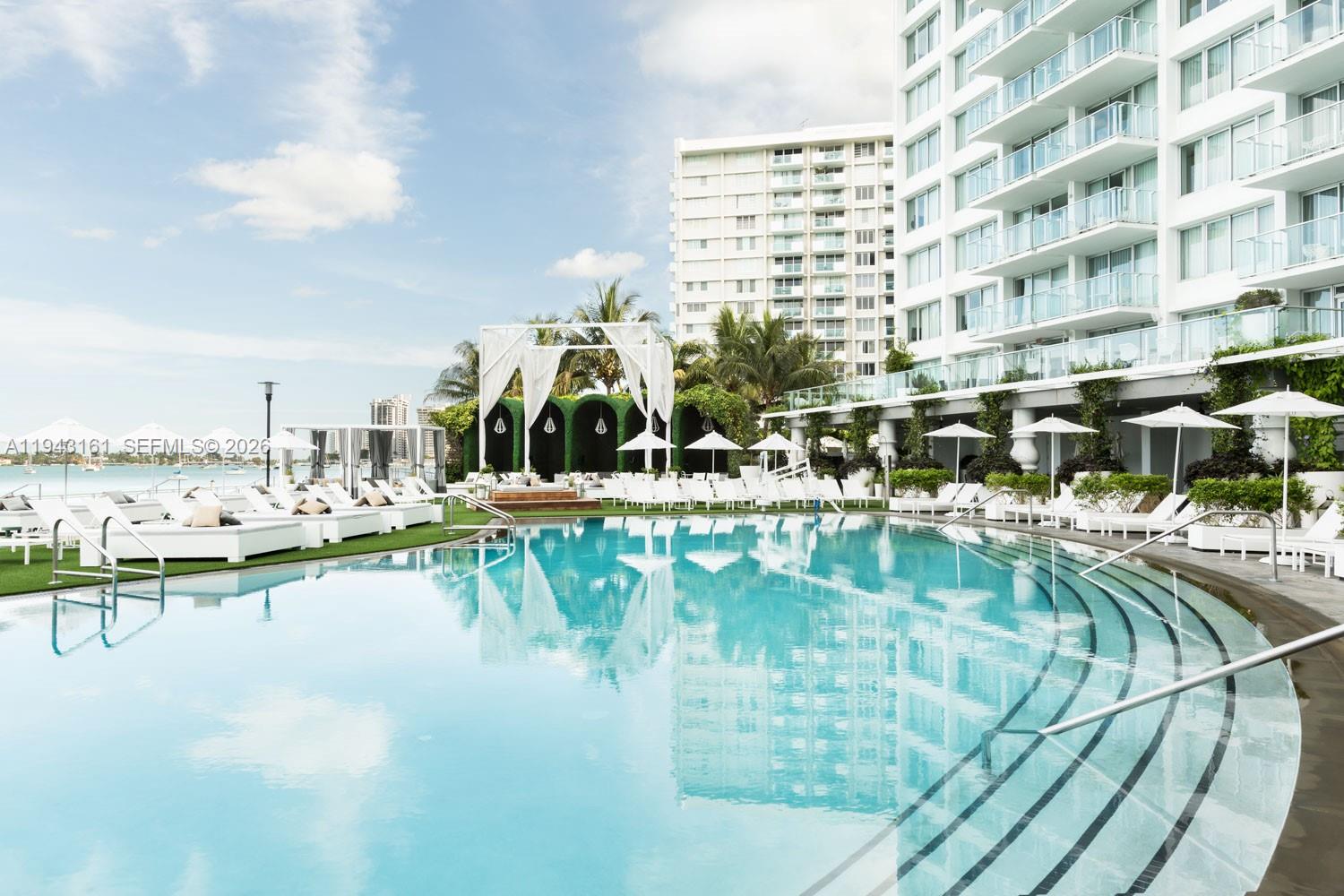 A swimming pool with lounge chairs and a wedding arch sits before a large building — 1100 West Ave # 307, Miami Beach FL 33139, MIAMI BEACH, FL