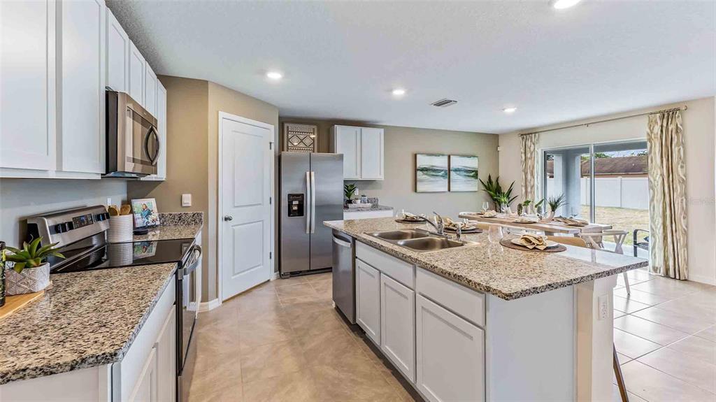 A kitchen features white cabinets, granite countertops, stainless steel appliances, and an island with seating — 35100 VALLEY RIDGE ROAD, DADE CITY, FL