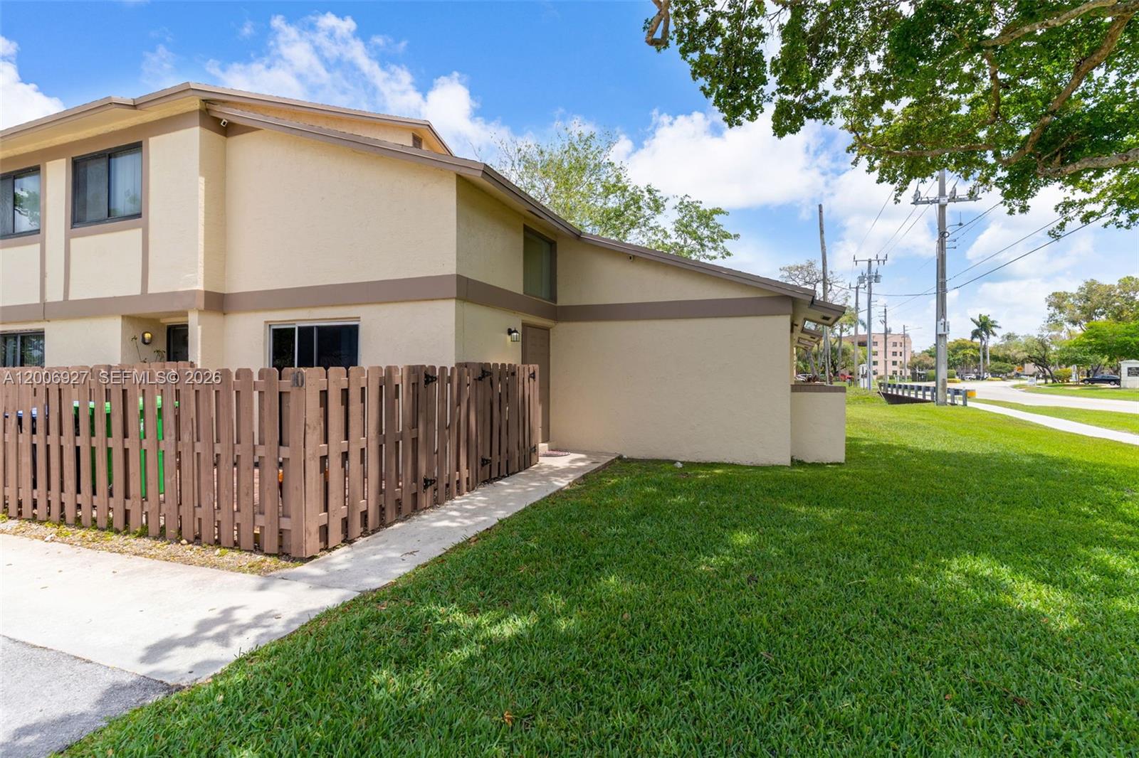 A tan two-story townhouse exterior features a brown wooden fence and a concrete walkway — 2950 NW 106th ave # 10, Sunrise FL 33322, SUNRISE, FL
