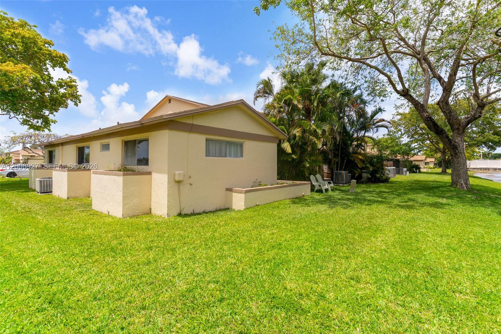A single-story beige house with a low-walled patio sits on a grassy lawn — 2950 NW 106th ave # 10, Sunrise FL 33322, SUNRISE, FL