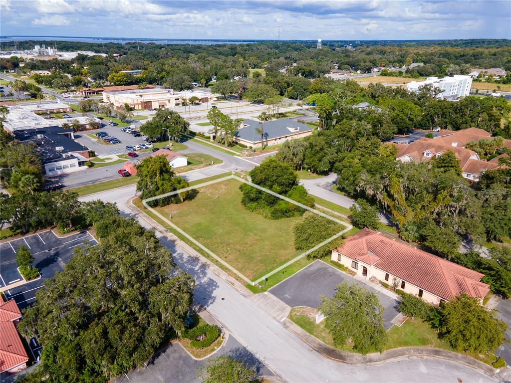 An aerial view shows a vacant, rectangular grass lot outlined in white near paved roads — 700 PHYSICIANS COURT, LEESBURG, FL
