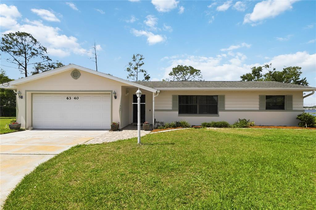 A single-story house with a white garage, light-colored siding, and a green lawn — 6340 JUDITH COURT, ST CLOUD, FL