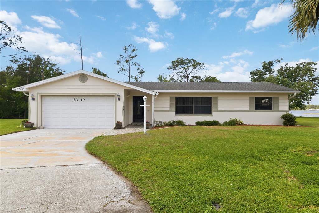 A single-story house with a white garage, beige siding, and a grassy front lawn — 6340 JUDITH COURT, ST CLOUD, FL