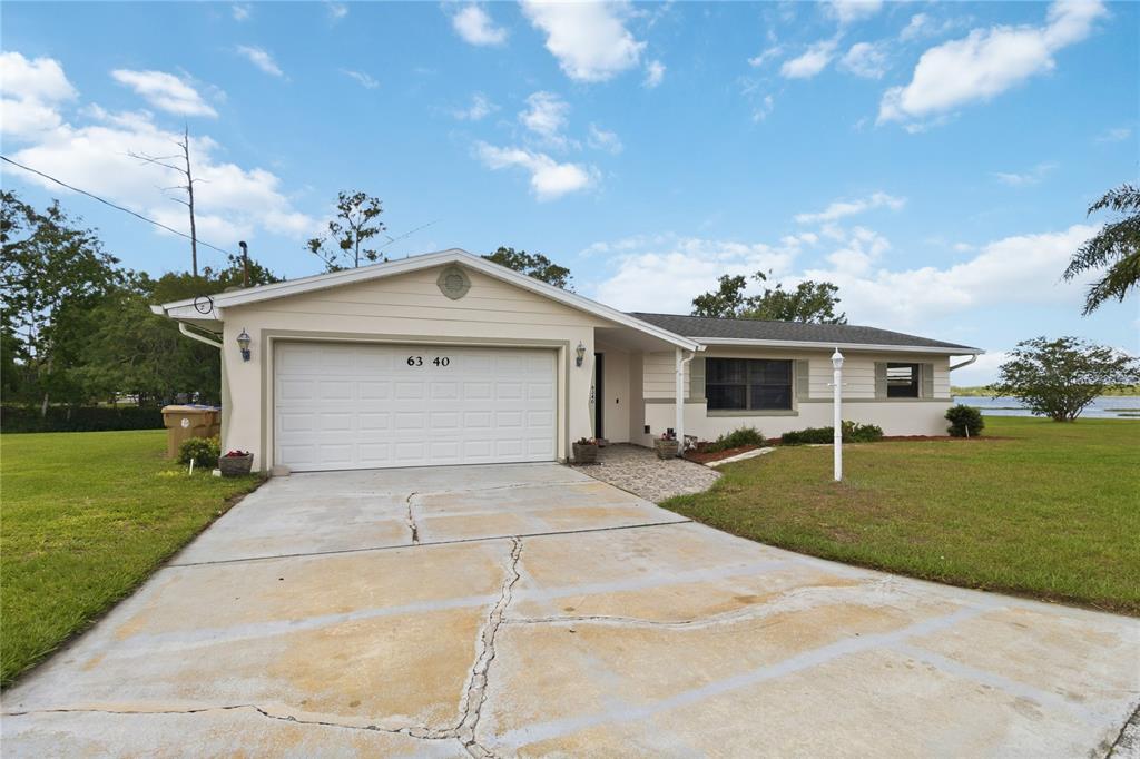 A single-story house with a white garage door, beige siding, and a cracked concrete driveway — 6340 JUDITH COURT, ST CLOUD, FL
